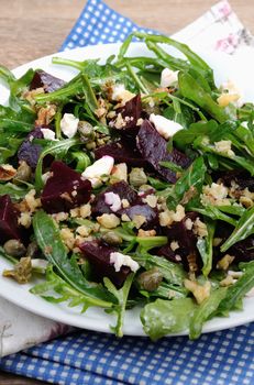 Beetroot salad with arugula with feta and capers, sprinkled with crushed nuts
