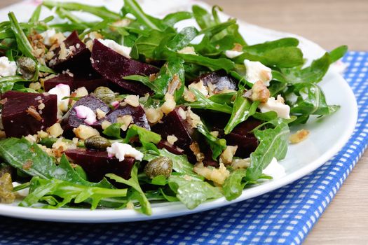 Beetroot salad with arugula with feta and capers, sprinkled with crushed nuts