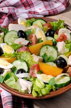 Vegetable salad with chicken and eggs, olives in lettuce leaves. Vertically  shot.