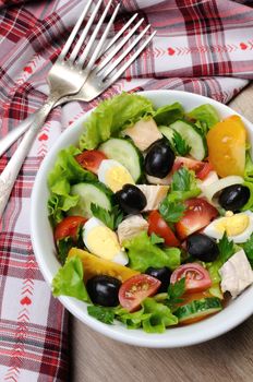 Vegetable salad with chicken and eggs, olives in lettuce leaves. Vertically  shot.