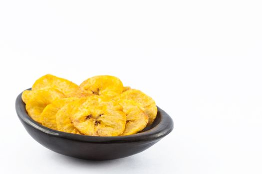 Plantain fryied coins in a traditional black clay bowl isolated on white background