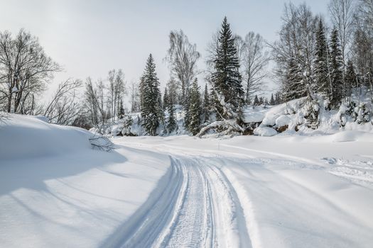 Snowmobile trail on the frozen forest river