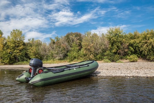 the green boat of pvc with the water-jet engine on the river bank