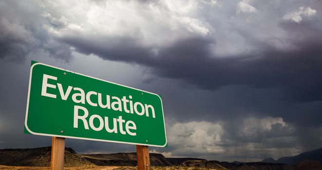 Evacuation Route Green Road Sign with Dramatic Clouds and Rain.