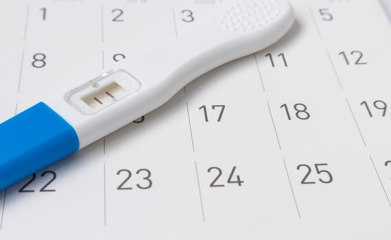 Pregnancy test on calendar background, health care concept