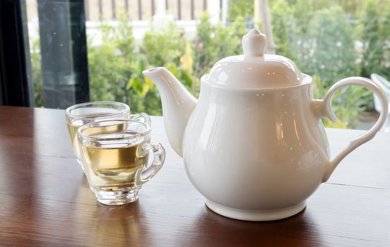 Tea pot and cups of tea on wood table with nature background