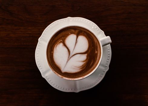 Closeup cup of hot coffee tulip latte art on wood table, vintage tone