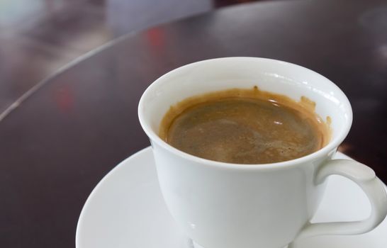 Cup of hot americano coffee on wood table in bakery shop