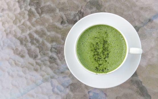 Closeup cup of matcha latte on glass table background