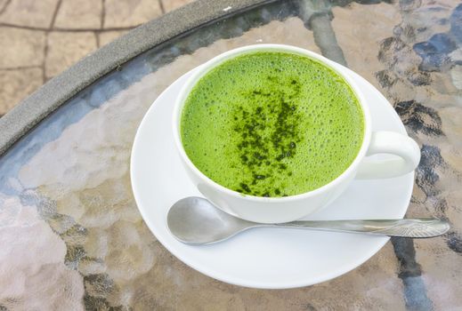 Closeup a cup of matcha latte or green tea on glass table background