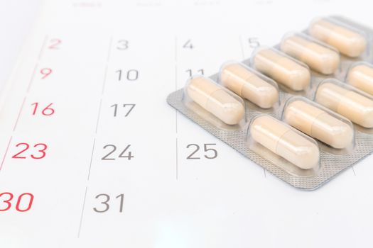 Close up pill with date of calendar background, health care and medicine concept