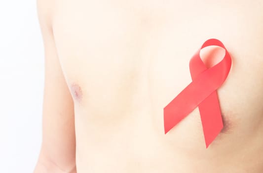 Closeup red ribbon on chest for AIDs awareness concept, health care and medicine