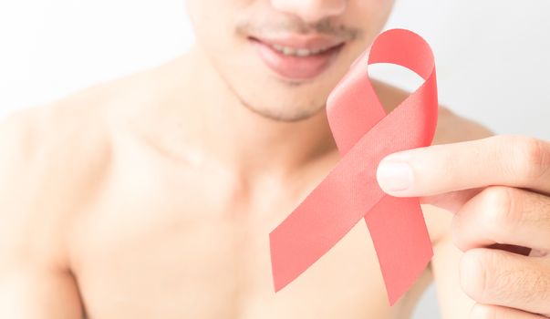 Hand hold red ribbon with blurred smile of man background for AIDs awareness concept