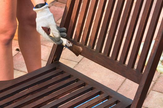 Painting and applying protective varnish on a wooden garden chair