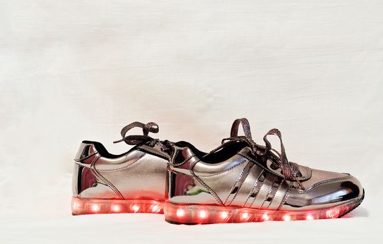 Original female sneakers with glowing soles isolated white background.