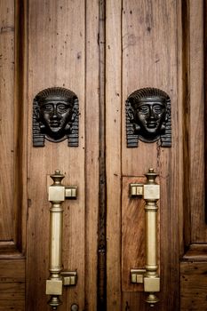 Detail of two bronze Sphinx heads on an old wooden door - around 100 years old, Italian palace in North Italy