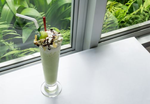 Closeup glass of cantaloupe melon frappe in coffee shop with green nature background