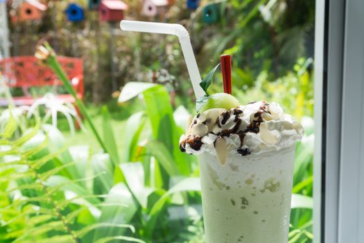 Closeup glass of cantaloupe melon frappe in coffee shop with green nature background
