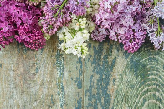 Lush multicolored bunches of lilac flowers on an old wooden background