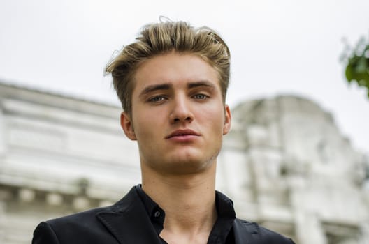 Handsome blond young man head-shot outdoors, looking at camera