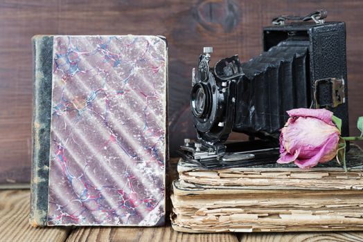 Still life in retro style: vintage photo camera, old books and the dried rose