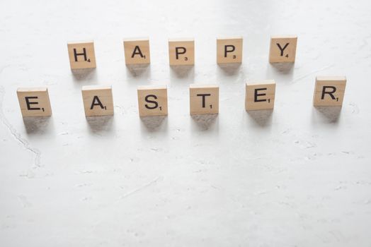 Easter concept: the inscription "Happy Easter", consisting of wooden game pieces with letters on a stone background