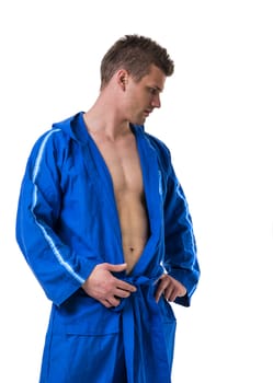 Handsome young man wearing blue bathrobe, looking down, isolated on white background