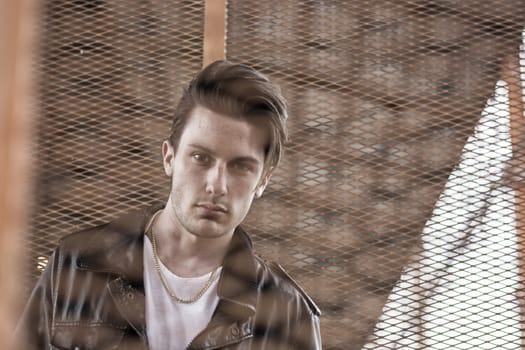 Handsome young man standing outdoors in urban environment on metal stairs