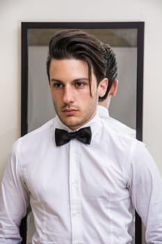 Mirror reflection of elegant handsome man wearing bow-tie