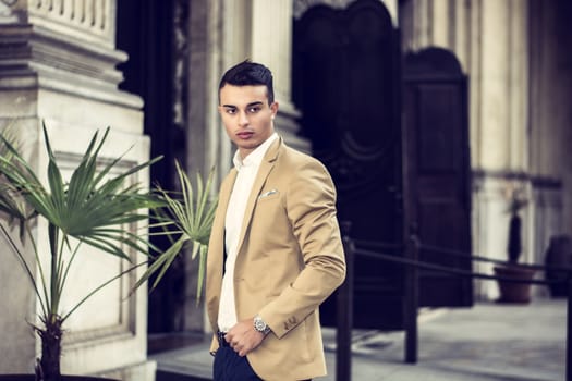 Elegant attractive young man outdoor wearing business suit, in European city