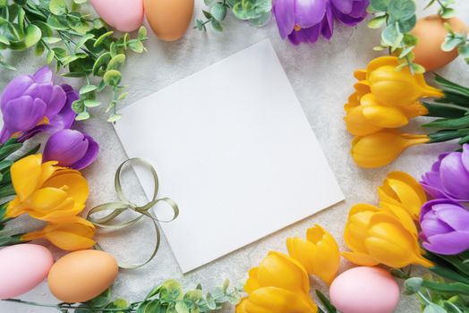 Easter card with blank white sheet surrounded by frame of yellow and purple crocus flowers and colorful Easter eggs