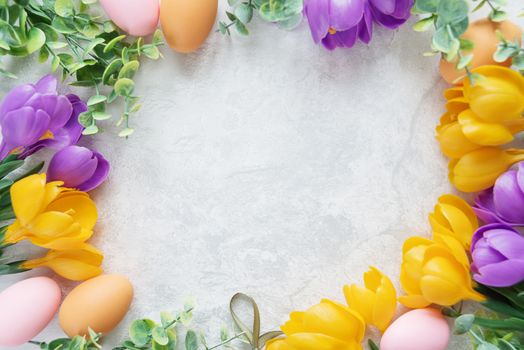 Easter card with frame of yellow and purple crocus flowers and colorful Easter eggs