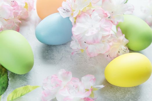 Beautiful delicate Easter composition with pink cherry flowers and multicolored Easter eggs on the stone background