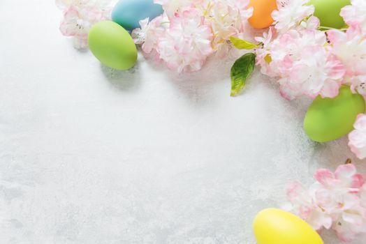 Beautiful delicate Easter frame with pink cherry flowers and multicolored Easter eggs