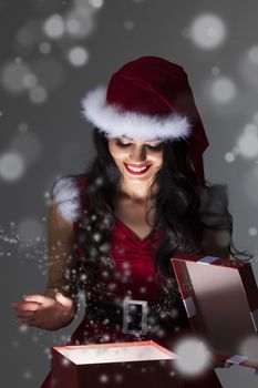 Beautiful Santa girl opening the magical Christmas present box