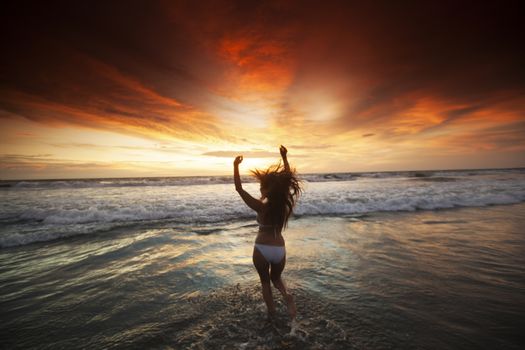 Happy Woman in bikini Jumping in Sea Sunset