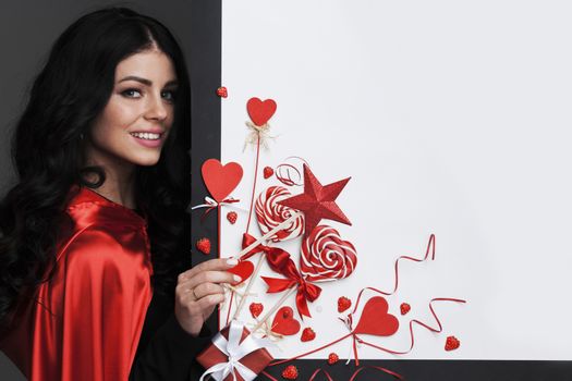 Woman with magic wand near Valentines day decoration and heart shaped lollipops isolated on white background