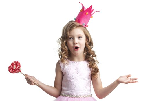Beautiful little candy princess girl in crown holding big pink heart lollipop and smiling