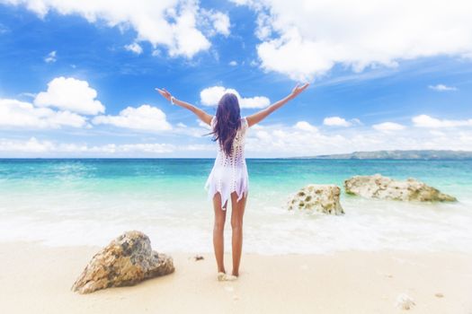 Woman in white dress posing in tropical sea beach