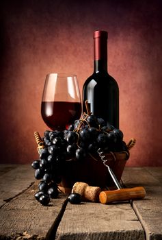 Red wine with basket of grape on table