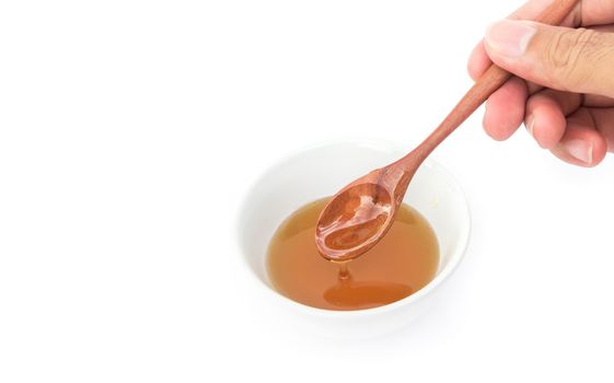 Closeup hand hold wooden spoon pour honey on white background, Healthy and beauty spa concept