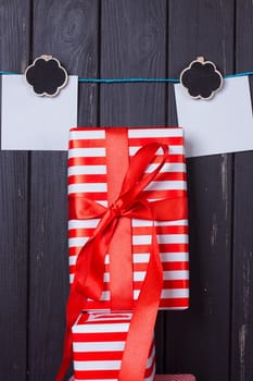 Gift box with a red bow on a wooden background With clothes pegs and place for text