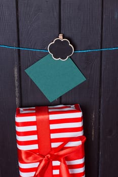 Gift box with a red bow on a wooden background With clothes pegs and place for text
