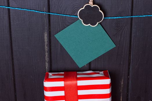 Gift box with a red bow on a wooden background With clothes pegs and place for text