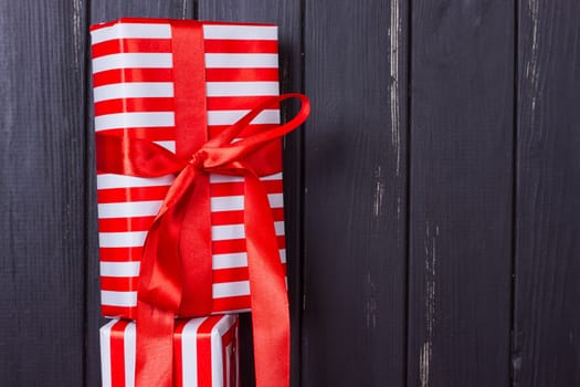 a slide of gifts in a red and white wrapper against a black wooden fence. Christmas presents