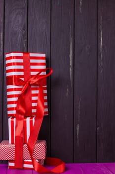 a slide of gifts in a red and white wrapper against a black wooden fence. Christmas presents