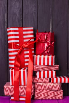 a slide of gifts in a red and white wrapper against a black wooden fence. Christmas presents
