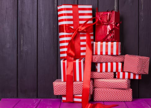 a slide of gifts in a red and white wrapper against a black wooden fence. Christmas presents