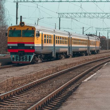 Old yellow passenger diesel train moving at the terminal