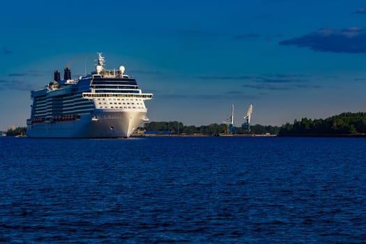 Giant white passenger ship moving past the port on a clear day